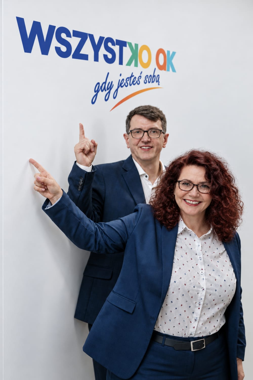 Ewa Mazurek i Arkadiusz Cimiński, założyciele Wszystko OK, wskazujący na napis „Wszystko OK, gdy jesteś sobą”